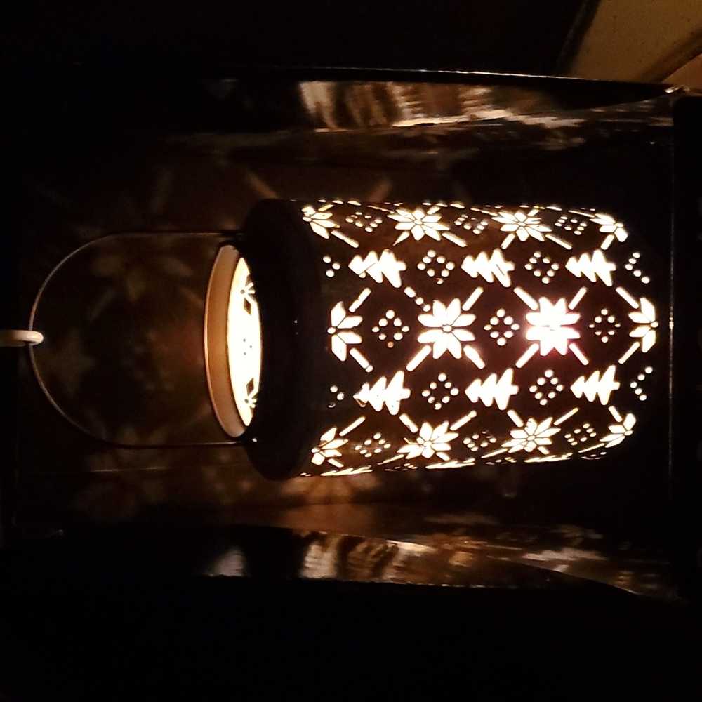 Brand new metal lantern. Has trees and snowflakes cut out in metal.